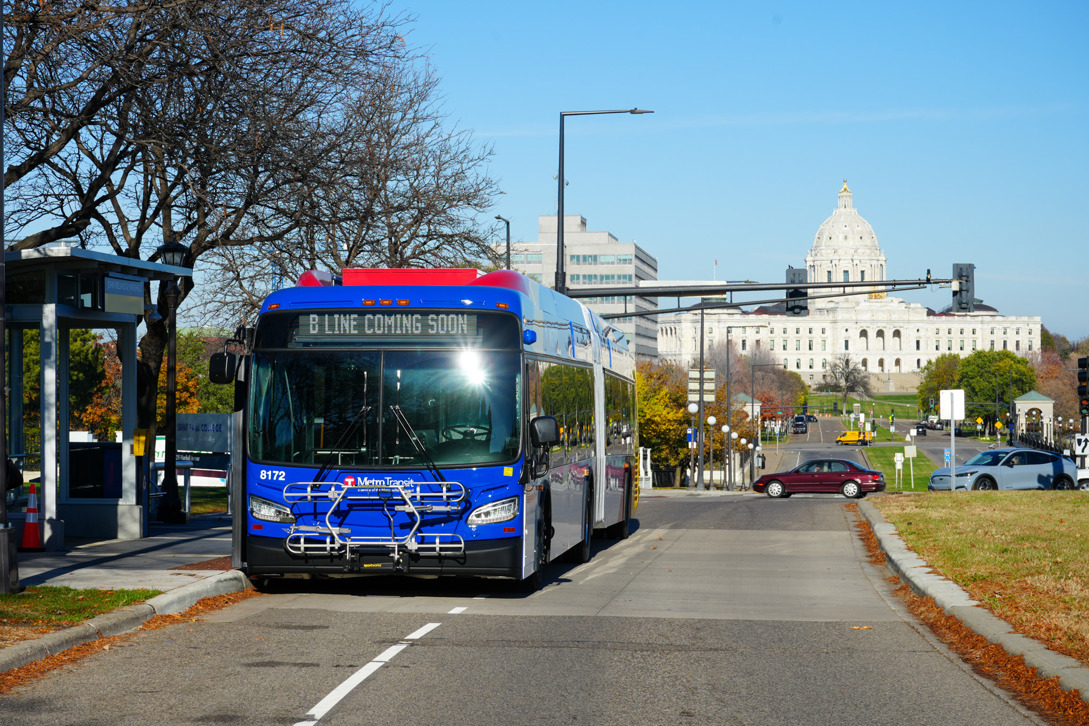 An image of a B Line bus stopping at a station with a view of the Minnesota State Capitol in the background.